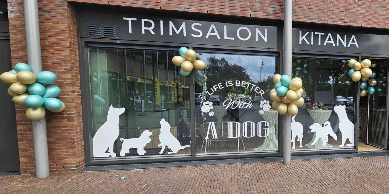 De etalage van Trimsalon Kitana aan de Markt, met witte hondensilhouetten op het raam