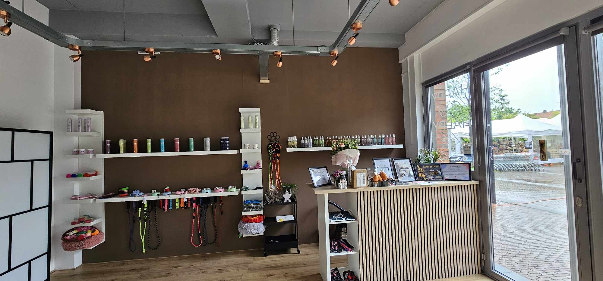 De salon van binnen: bruine wand met halsbanden en riemen, houten balie en het raam op de Markt
